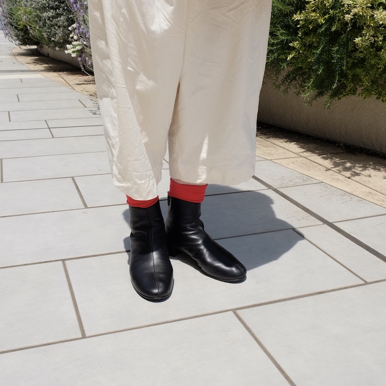 白いバンツと黒いブーツを合わせて、差し色に赤いソックス