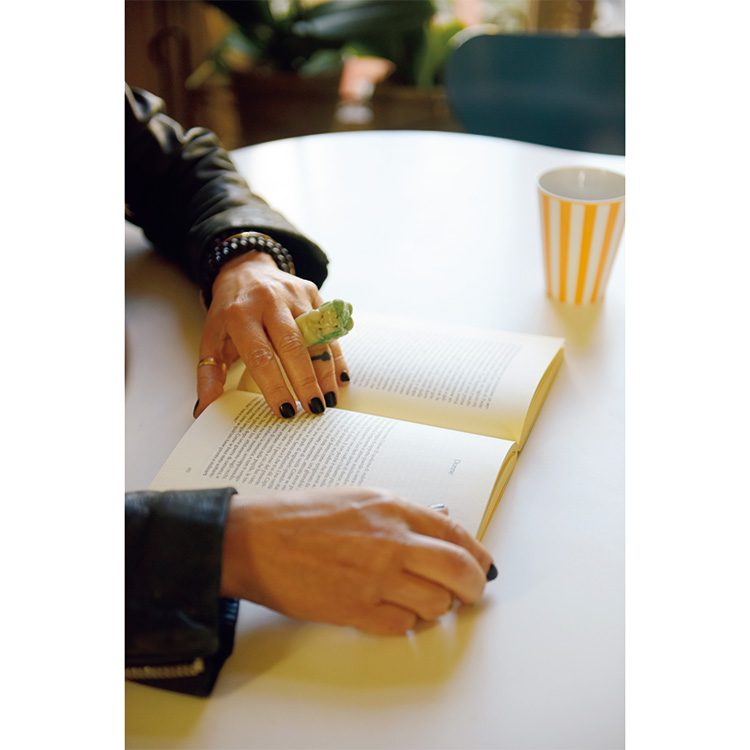テーブルの上にマグカップと見開きの本にロベルタ・モラン＝コルヴォさんの手が添えられている写真