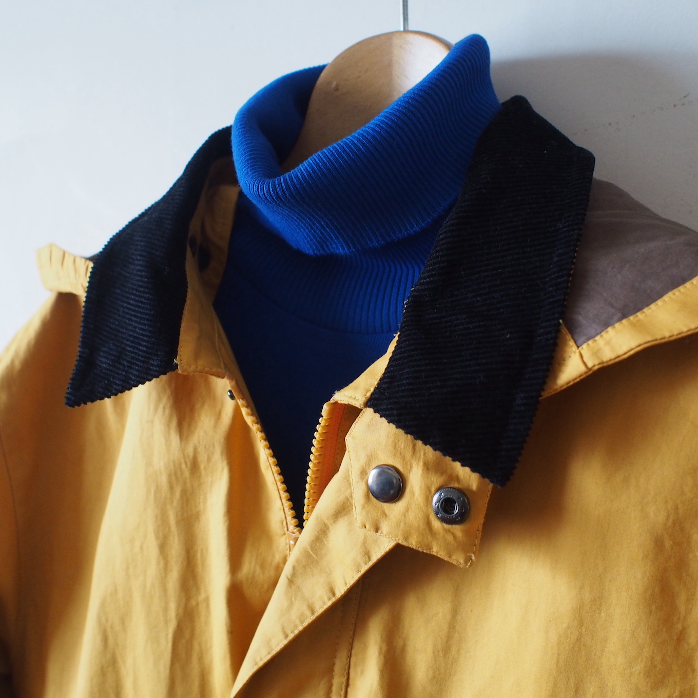 ブルーのハイネックとイエローのコートがハンガーにかかっている