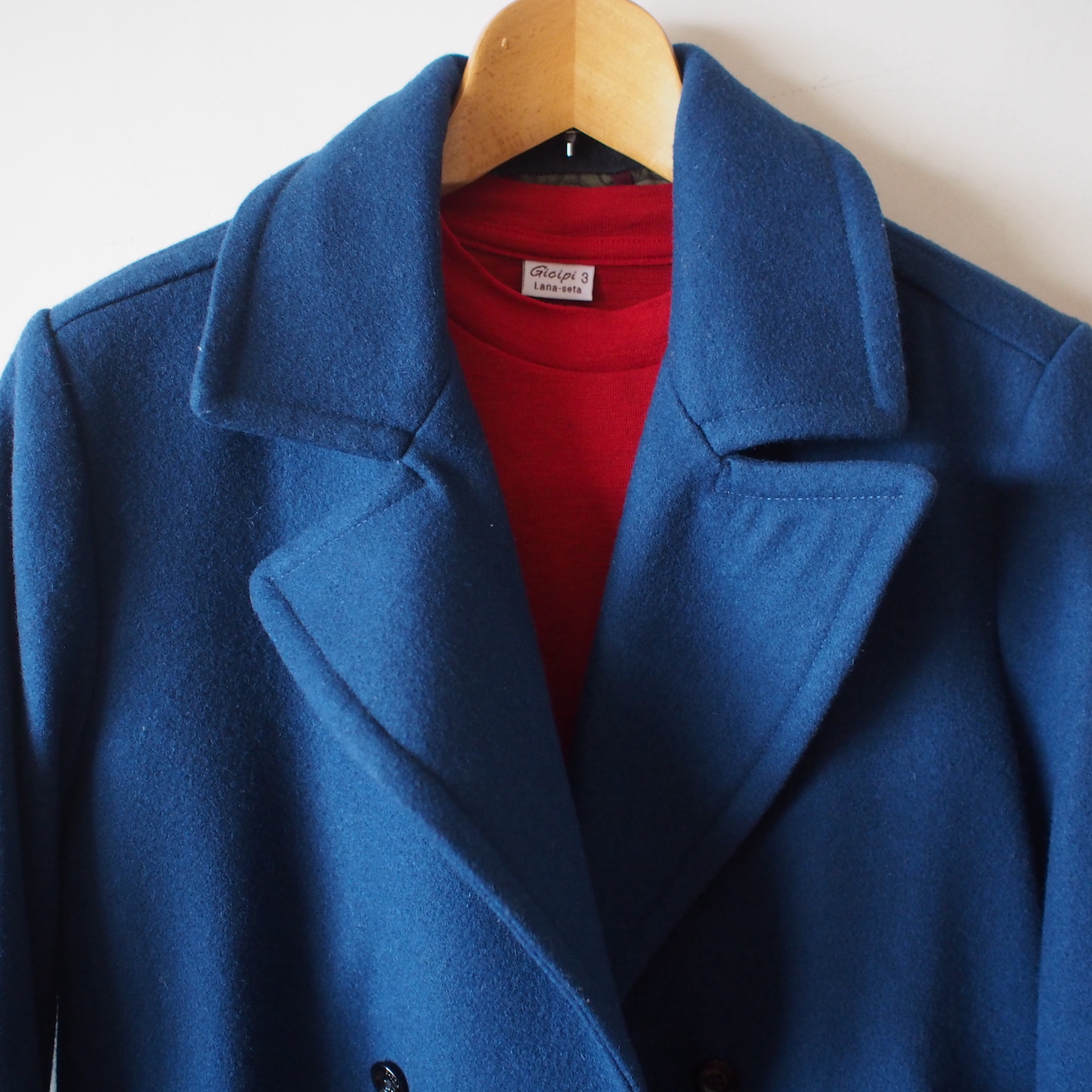 ブルーのコートと赤のインナーがハンガーにかかっている
