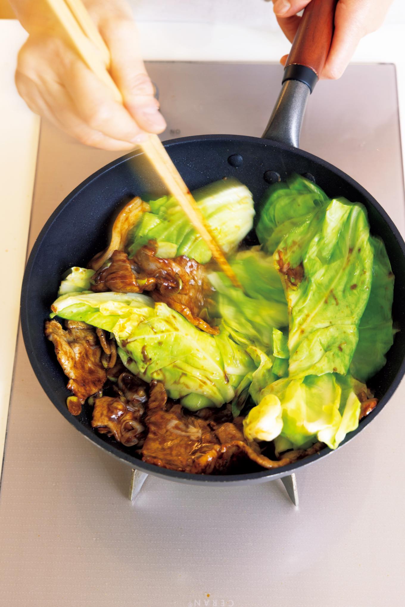 キャベツと肉をフライパンで炒めている様子