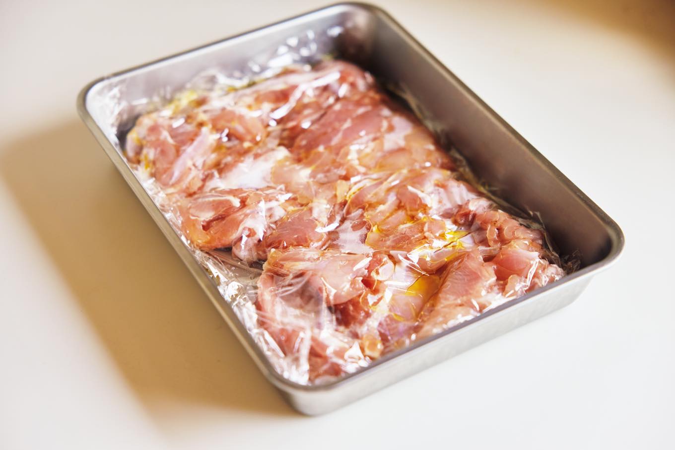 オイルをつけた鶏肉をラップで覆う