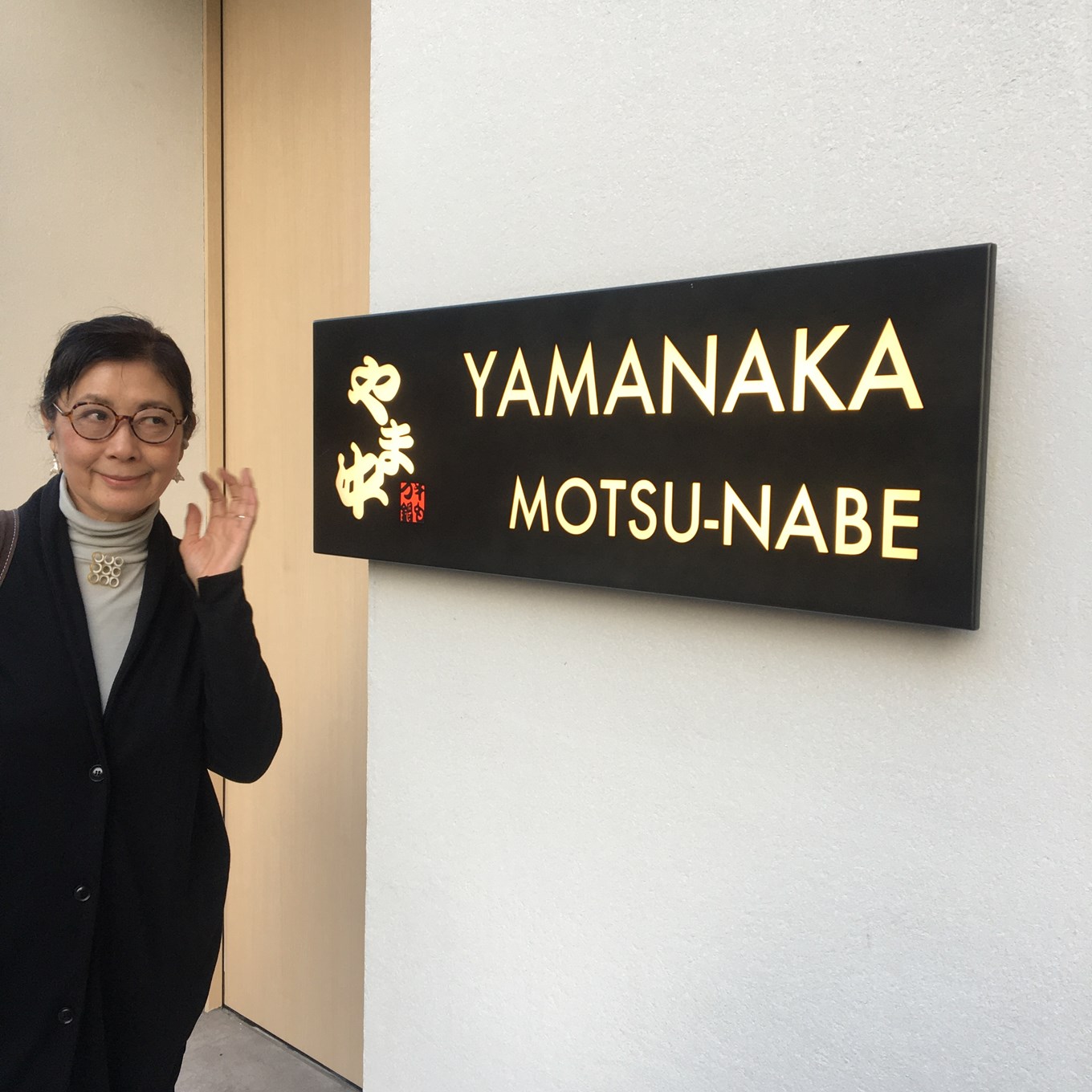 博多もつ鍋 やま中 の看板の前に立つ石黒美穂子