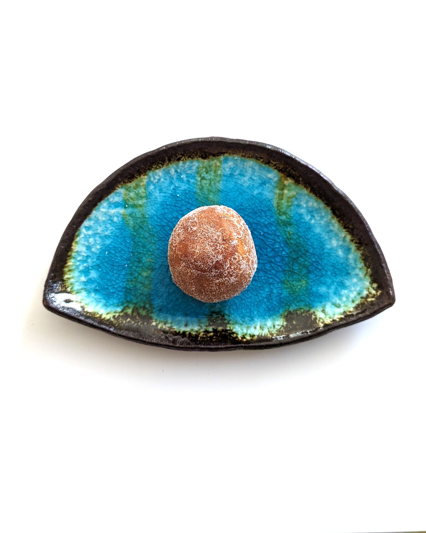 白いテーブルの上の青い皿の上の茶色のあんドーナツ