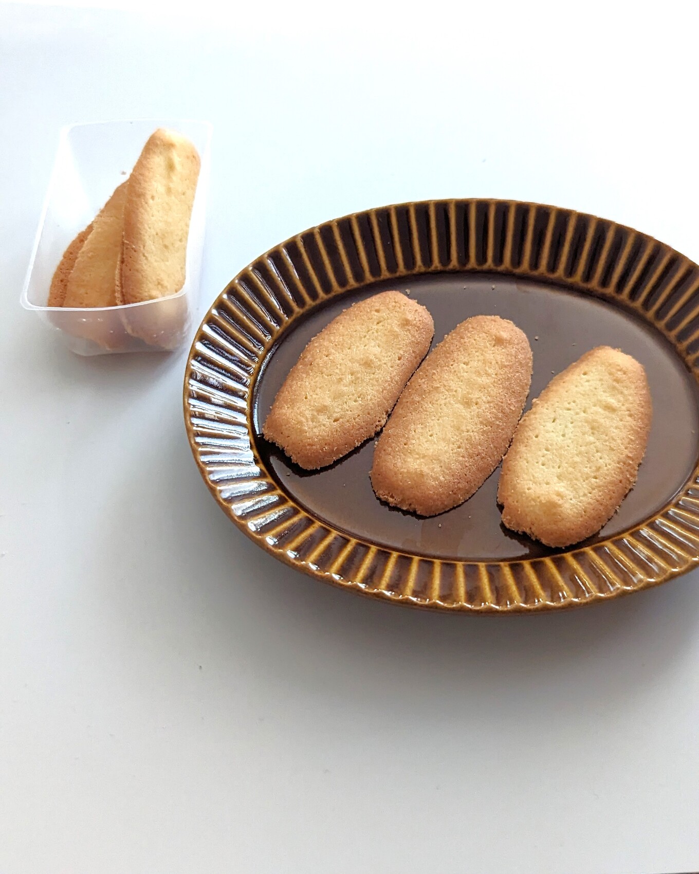 白いテーブルの上の茶色い皿の上に並べたクッキー