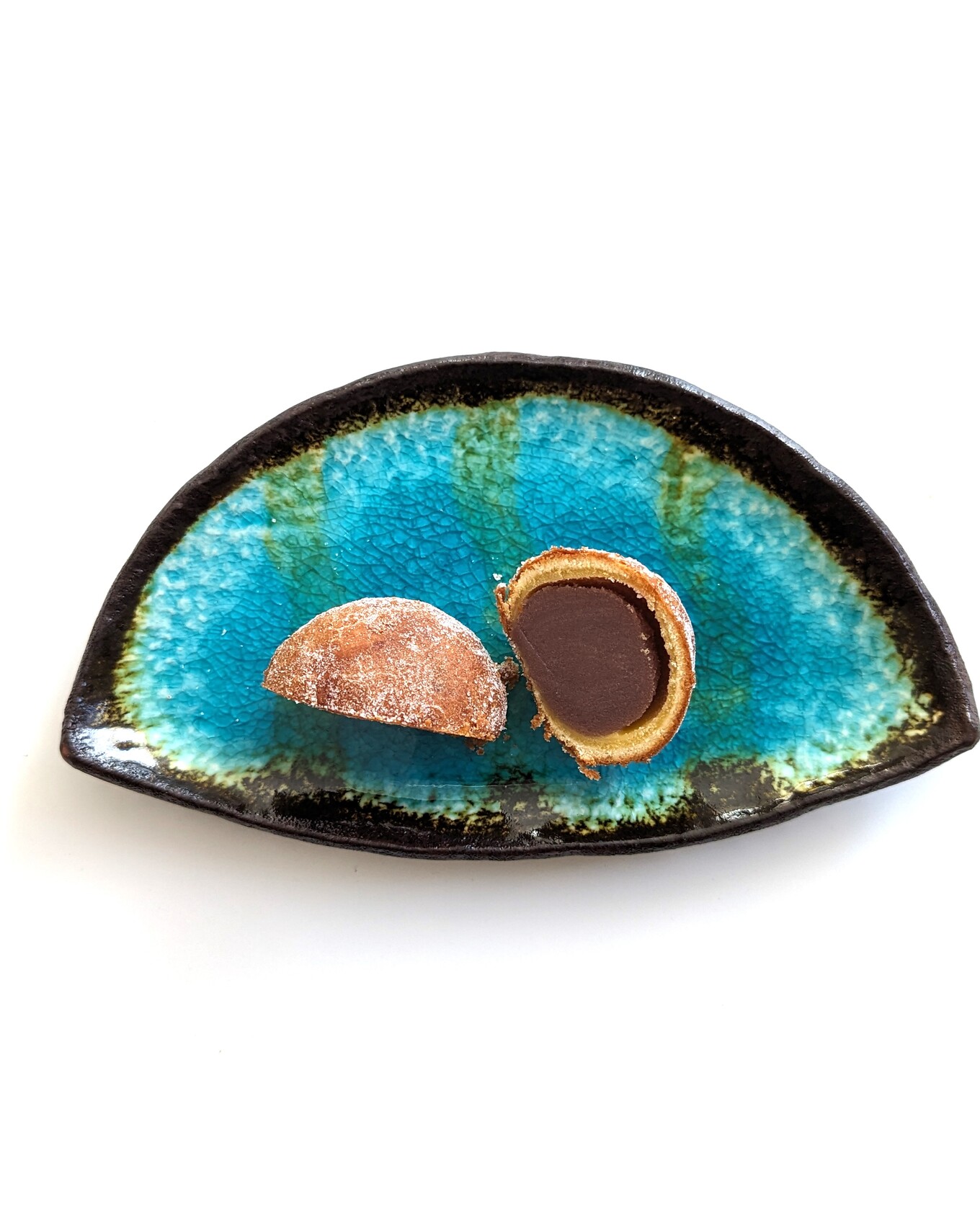 白いテーブルの上の青い皿の上のあんこの入ったドーナツ